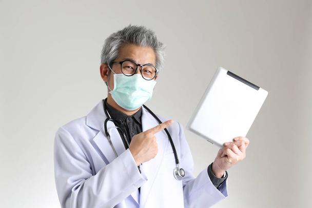 Le médecin asiatique principal avec masque sur le fond blanc. - Photo, image
