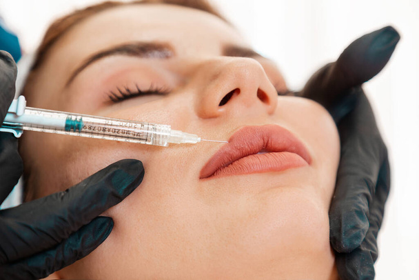 Esztétikai orvoslás. A kozmetikus az ajakba fecskendezett orvosi injekciókkal készíti. Közelkép a női arcról. A plasztikai sebészet és a kozmetológia fogalma. - Fotó, kép