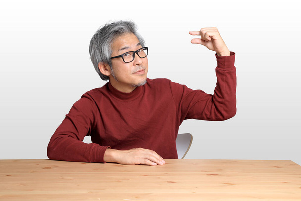 The Senior Asian man sitting at the desk on the white background. - Photo, Image