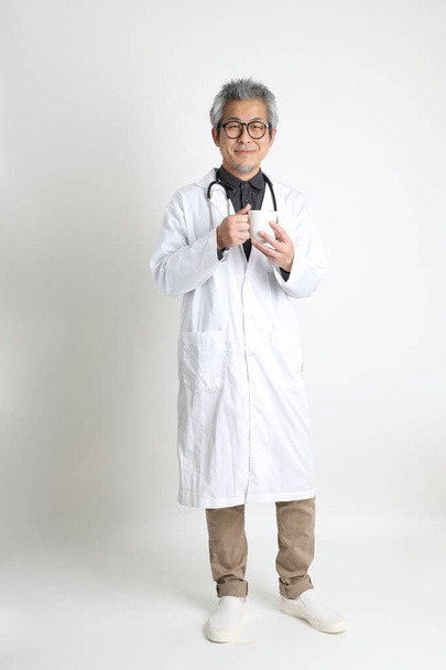 The senior Asian physician on the white background. - Photo, Image