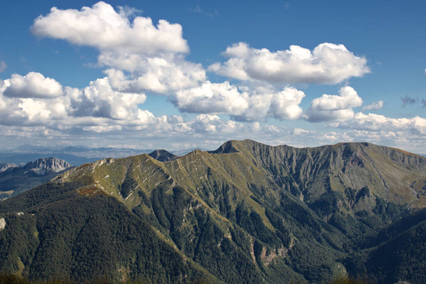 A high angle shot of mountainous landscape with layers of peaks seen under cloudy sky - Foto, afbeelding