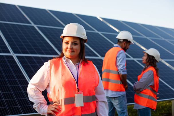 Serious woman engineer is standing on a background of solar panels - Фото, изображение