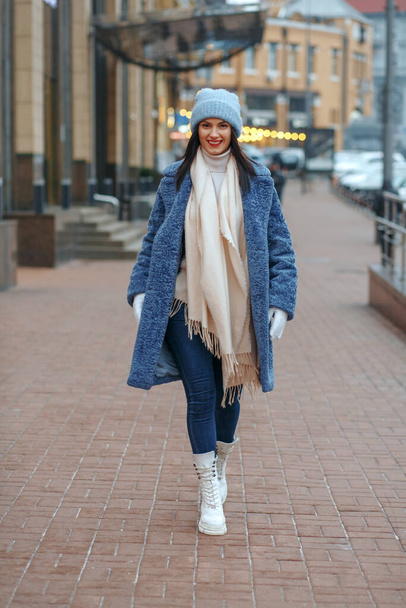 Femme brune élégante en manteau marchant à la ville en hiver - Photo, image