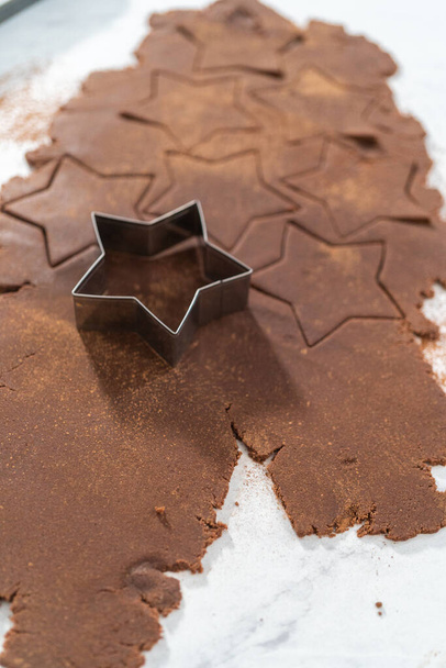 Κοπή κροτίδων σοκολάτας σε σχήμα αστεριού από τη ζύμη με κόφτη μπισκότων. - Φωτογραφία, εικόνα