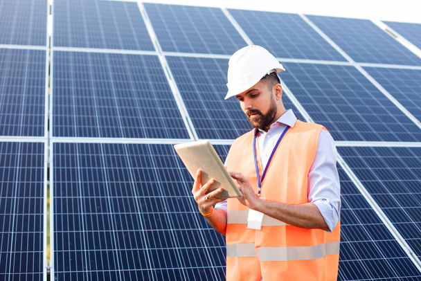 Ingénieur avec une tablette se tient sur le fond d'une station solaire - Photo, image