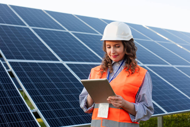 Female engineer is working with tablet at solar station - Фото, зображення