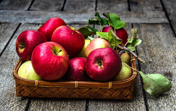Elmaları hasat et, hasır bir sepetin içinde, ahşap bir masada.. - Fotoğraf, Görsel