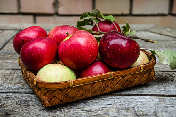 Harvest apples from the home garden in a wicker basket, on a wooden table. - Photo, Image