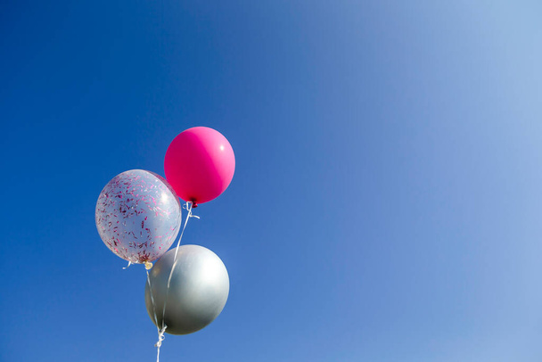 Τρία πολύχρωμα μπαλόνια ηλίου γενεθλίων αιωρούνται στον ουρανό. Αντιγραφή διαθέσιμου χώρου για το κείμενο. - Φωτογραφία, εικόνα