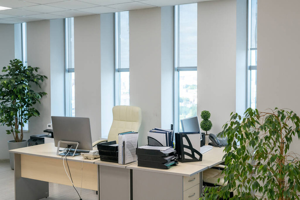 Pareja de escritorios con monitores de ordenador y documentos de pie a lo largo de ventanas - Foto, Imagen