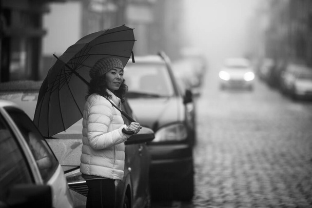 Una donna sta in strada con il tempo nuvoloso. Foto in bianco e nero. - Foto, immagini