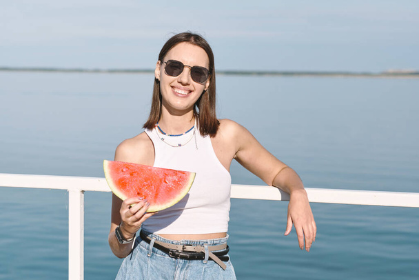 Pretty female in sunglasses holding big slice of watermelon - Foto, immagini