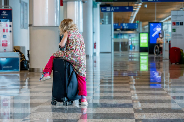Cute blonde girl with travel luggage at the airport. - Foto, imagen
