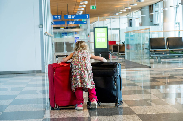 Χαριτωμένο ξανθό κορίτσι με ταξιδιωτικές αποσκευές στο αεροδρόμιο. - Φωτογραφία, εικόνα