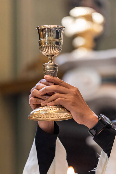 Вознесение чаши с сакраментальным вином во время католической литургии Евхаристии - Фото, изображение