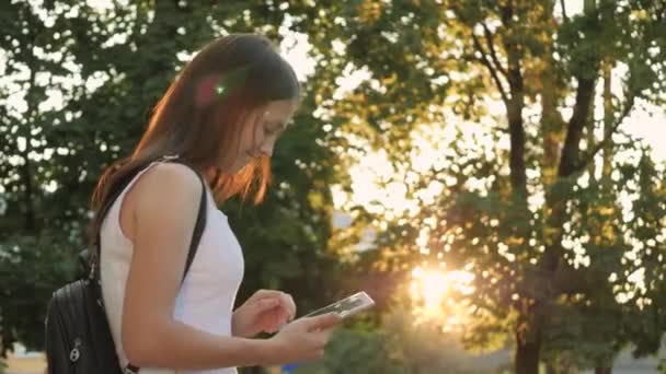 Şehrin güneş ışınlarında bir tablette okuyan, çevrimiçi bir mağazada gün batımında online alışveriş yapan, sosyal ağlarda e-postaları kontrol eden, sohbet eden, bilgi kaynaklarında kitap okuyan ve haberler okuyan bir kız. - Video, Çekim