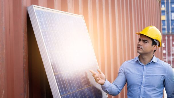 Αμερικανός μηχανικός άνθρωπος φορώντας κράνος ασφαλείας και δείχνοντας χέρι στην ηλιακή κυψέλη και εμπορευματοκιβωτίων έννοια μηχανικής υποβάθρου ενέργειας  - Φωτογραφία, εικόνα