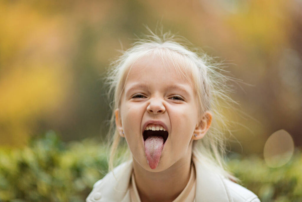 Cute stylish little girl with long blonde hair walking in autumn park. Autumn kids fashion. Happy childhood. Lifestyle portrait. Caucasian child 6 years old outdoor - Φωτογραφία, εικόνα