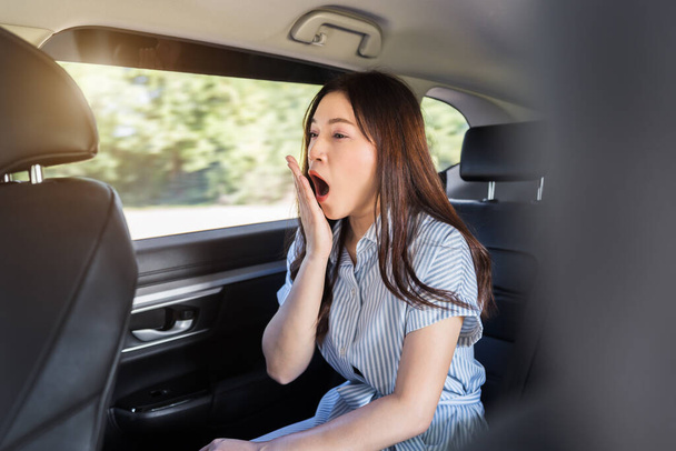 sleepy young woman yawning while sitting in the back seat of car  - Foto, imagen