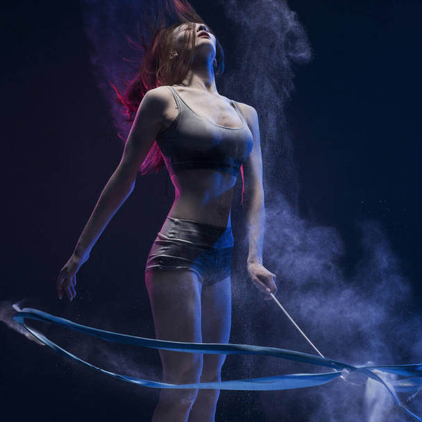 Woman exercising with ribbon in dust cloud view - 写真・画像