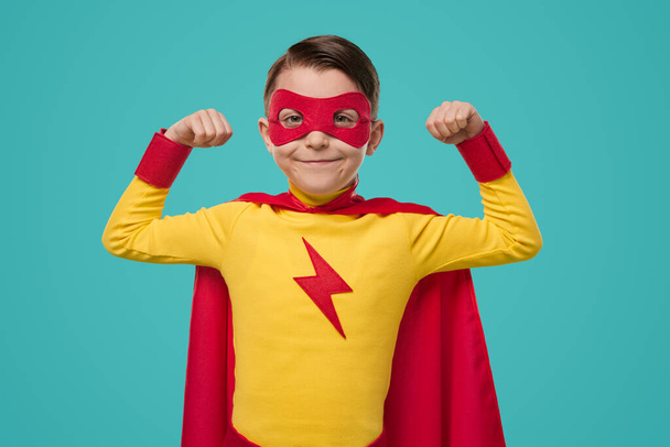 Proud superhero kid in mask showing biceps - Foto, Bild