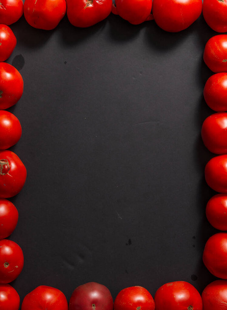 Black background with red tomatoes around the edges. - Foto, Bild