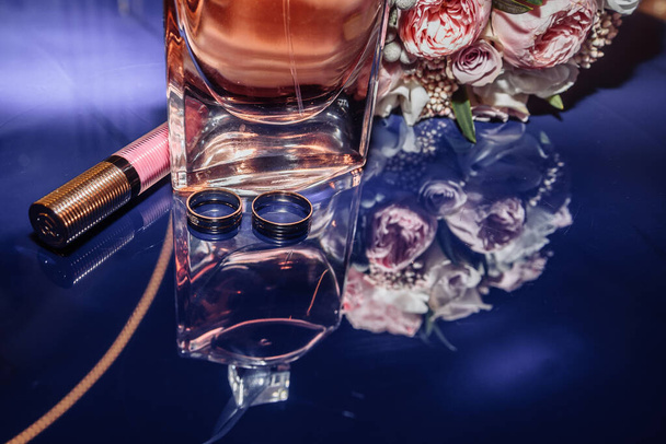 золотые обручальные кольца в стеклянной коробке лежат рядом со свадебным букетом с аустом. эстетика и детали - Фото, изображение