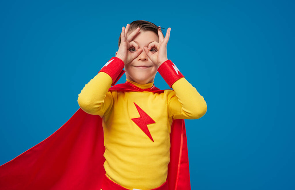Happy superhero kid looking through fingers - Foto, Imagem