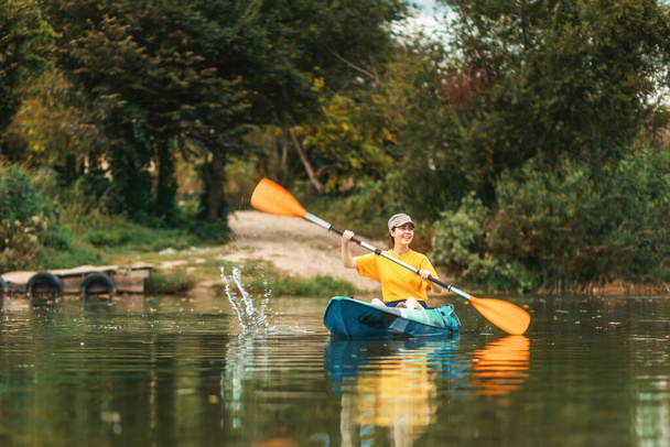 Dünya Turizm Günü. Nehirde mavi kanoyla yüzen mutlu beyaz kız. Uzayı kopyala Kano konsepti. - Fotoğraf, Görsel