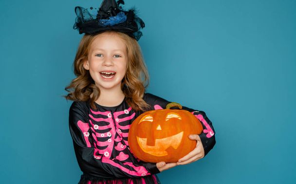¡Feliz Halloween! Linda niña riendo en traje de bruja en fondo de pared azul.  - Foto, imagen