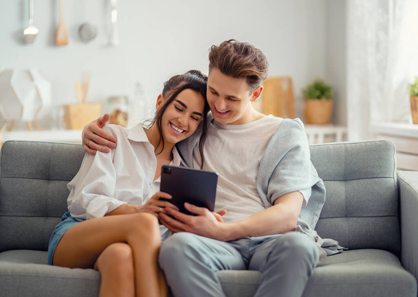 Young couple is using tablet pc. Woman and man having fun staying at home. - Foto, Imagen