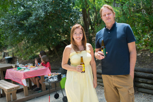 Portrait of happy husband and wife drinking beer at picnic - Foto, imagen