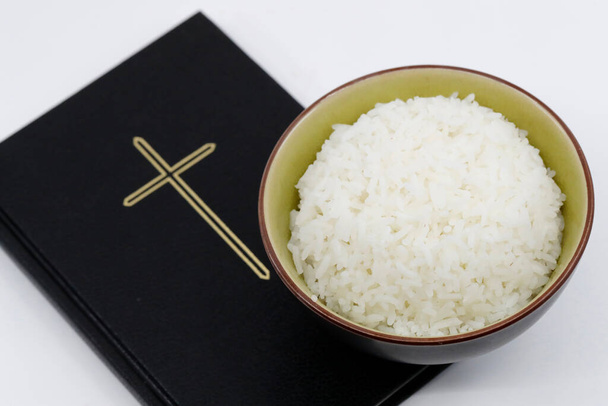 Schaal rijst en bijbel tijdens de vastentijd. Een plechtige religieuze viering die begint op Aswoensdag.  - Foto, afbeelding