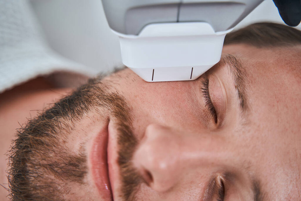 Mužský pacient ležící se zavřenýma očima neinvazivní proces stahování kůže - Fotografie, Obrázek
