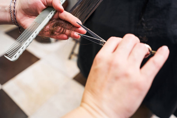 Close up of stylist cutting brunette hair - Фото, зображення