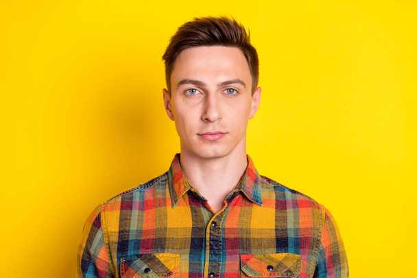 Portrait of attractive minded serious brown-haired guy wearing checked shirt isolated over bright yellow color background - Fotografie, Obrázek