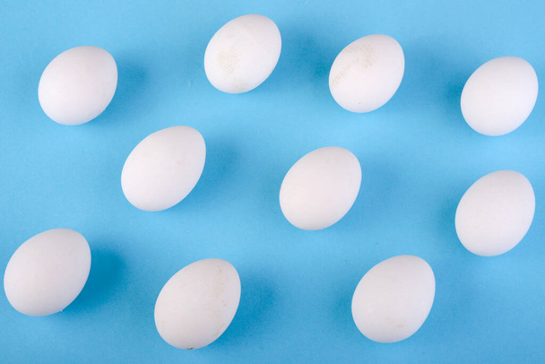 diez huevos blancos sobre fondo azul claro - Foto, Imagen