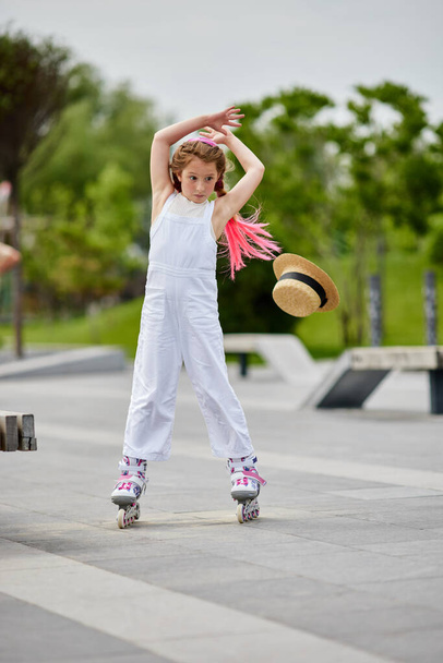 Cute little child girl on roller skates at park - Zdjęcie, obraz