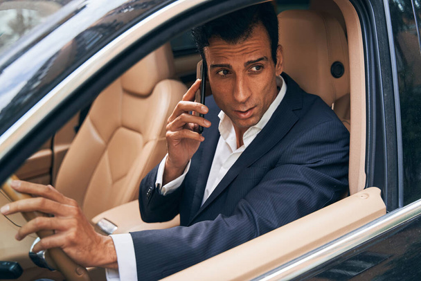 Businessman sitting in car and talking on phone - Foto, Imagen