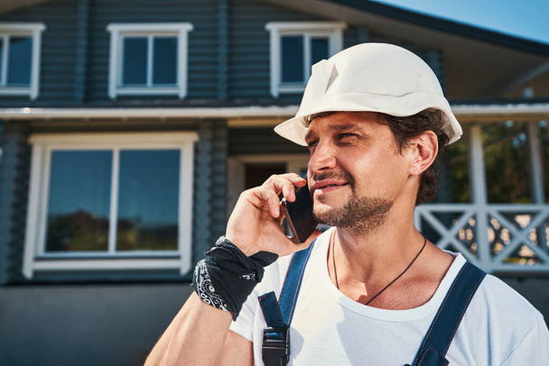 Builder having a phone call on hot summer day - Фото, зображення