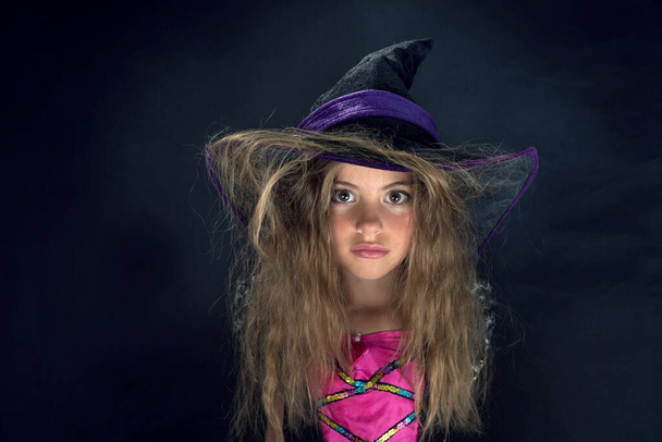 Tyttö pukeutunut noidaksi ja leveälierinen hattu halloweenina. - Valokuva, kuva