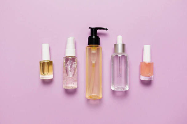 Organic cosmetics packaging design. Flat lay, top view clear glass pump bottle, brush jar, moisturizing serum jar on a purple background. Natural cosmetics SPA - Φωτογραφία, εικόνα