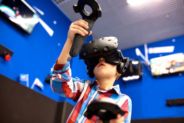 современные технологии, игры и концепция людей - мальчик в гарнитуре виртуальной реальности или 3D очки, играющий в видеоигру в игровом центре
 - Фото, изображение