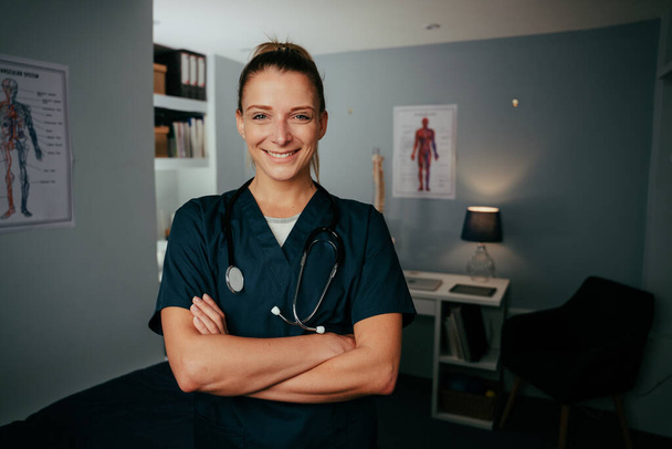 Caucasian female nurse standing with arms crossed in medical clinic - Foto, afbeelding