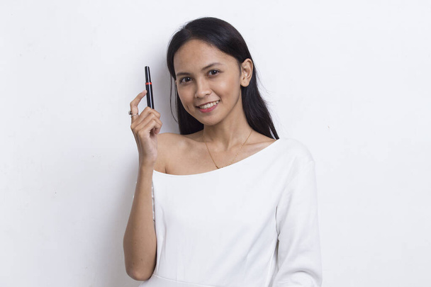 красивая молодая азиатская женщина с помощью помады изолированы на белом фоне - Фото, изображение