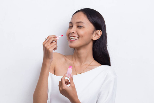 красивая молодая азиатская женщина с помощью помады изолированы на белом фоне - Фото, изображение