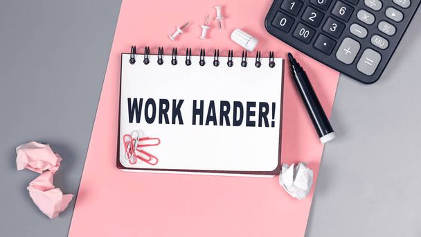 Die Worte Work Harder auf einem weißen Notizbuch geschrieben. Nahaufnahme einer persönlichen Agenda. Ansicht von oben. Bürokonzept. Notizbuch auf rosa und grauen Hintergrund - Foto, Bild