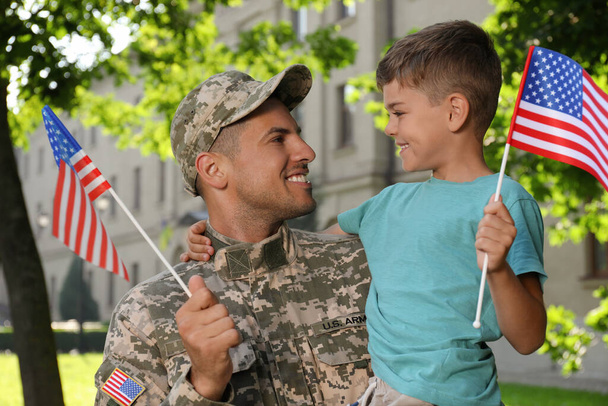 Soldato e suo figlio con bandiere americane all'aperto. Giornata dei veterani negli Stati Uniti - Foto, immagini