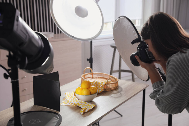 Young woman with professional camera taking photo of lemons in studio - Φωτογραφία, εικόνα