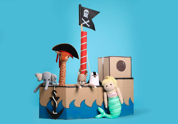 Pirate cardboard ship and toys on turquoise background - 写真・画像